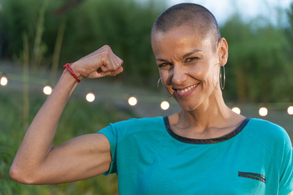 Powerful woman with her fist up, shaved hair and a big smile. Empowered confident and strong female
